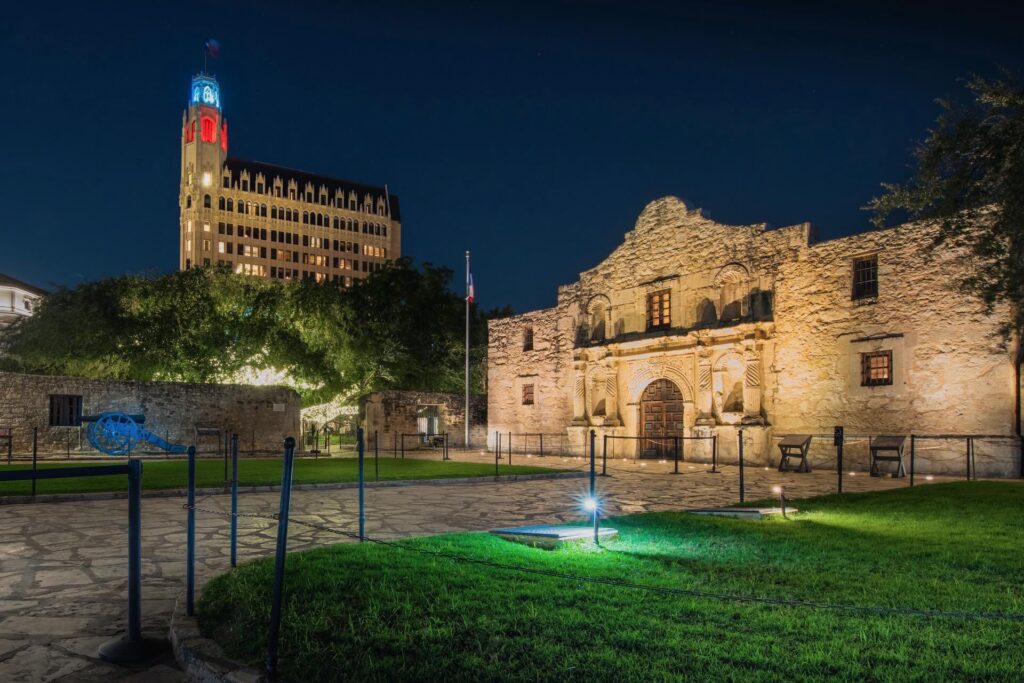 The Alamo at night with the Emily Morgan hotel in the background.